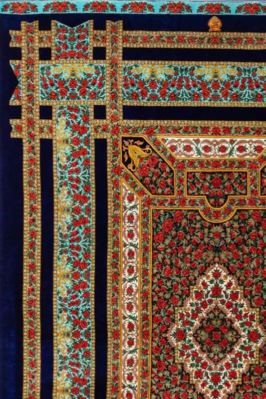 Qom silk carpet featuring red roses on a black background, showcasing Persian weaving expertise with traditional patterns and exceptional durability.