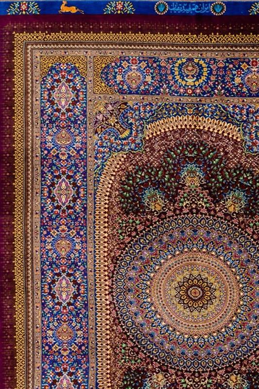 "Eternal Harmony" silk carpet with a deep burgundy background and blue and gold borders, showcasing intricate patterns and Persian weaving craftsmanship.