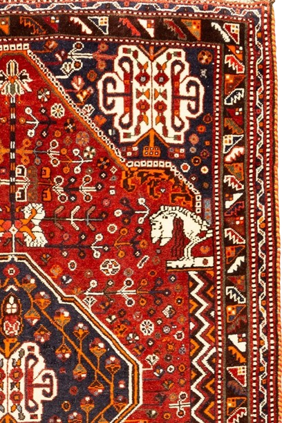 Image of an antique Persian handwoven rug with geometric and floral patterns.