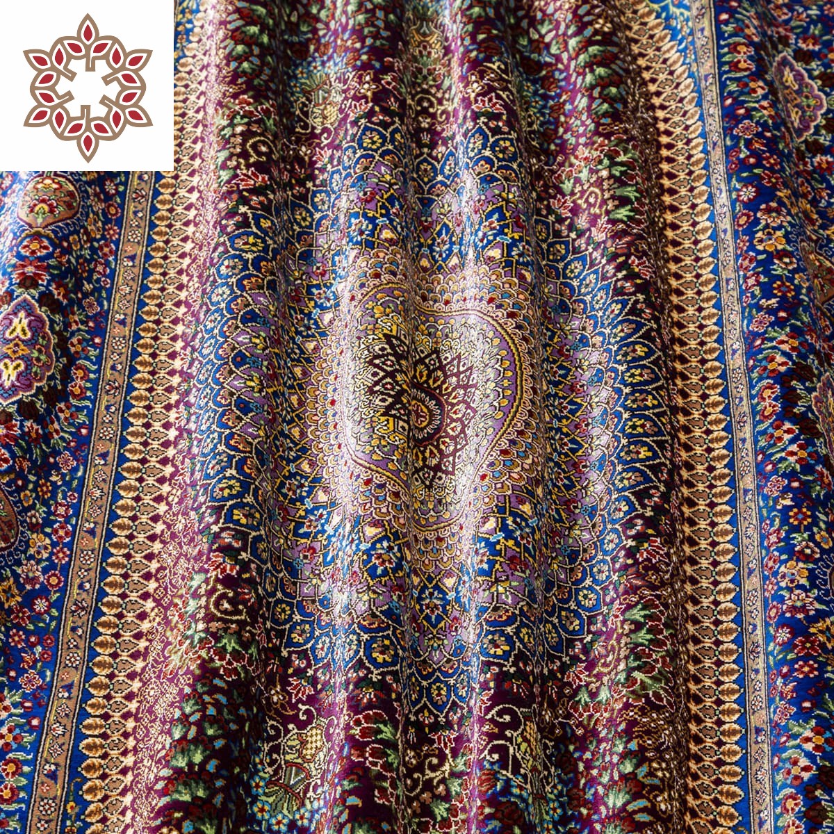 "Eternal Harmony" silk carpet with a deep burgundy background and blue and gold borders, showcasing intricate patterns and Persian weaving craftsmanship.